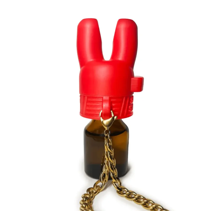 Super Sniffer Poppers Cap with Chain: A bold and vibrant red bunny-shaped Super Sniffer poppers cap atop a small amber bottle, accessorized with an elegant gold chain, making it a stylish and functional accessory for aroma enthusiasts.