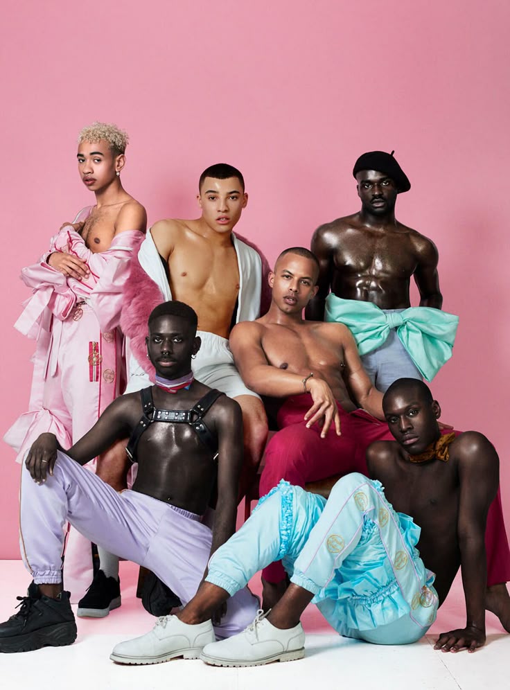 What is genderfluid? Group of genderfluid and androgynous models posing in pastel-colored, expressive fashion against a pink background, celebrating diverse gender expression.